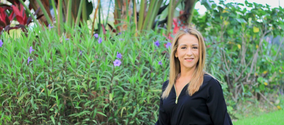 Image of Marilu standing in front of a garden